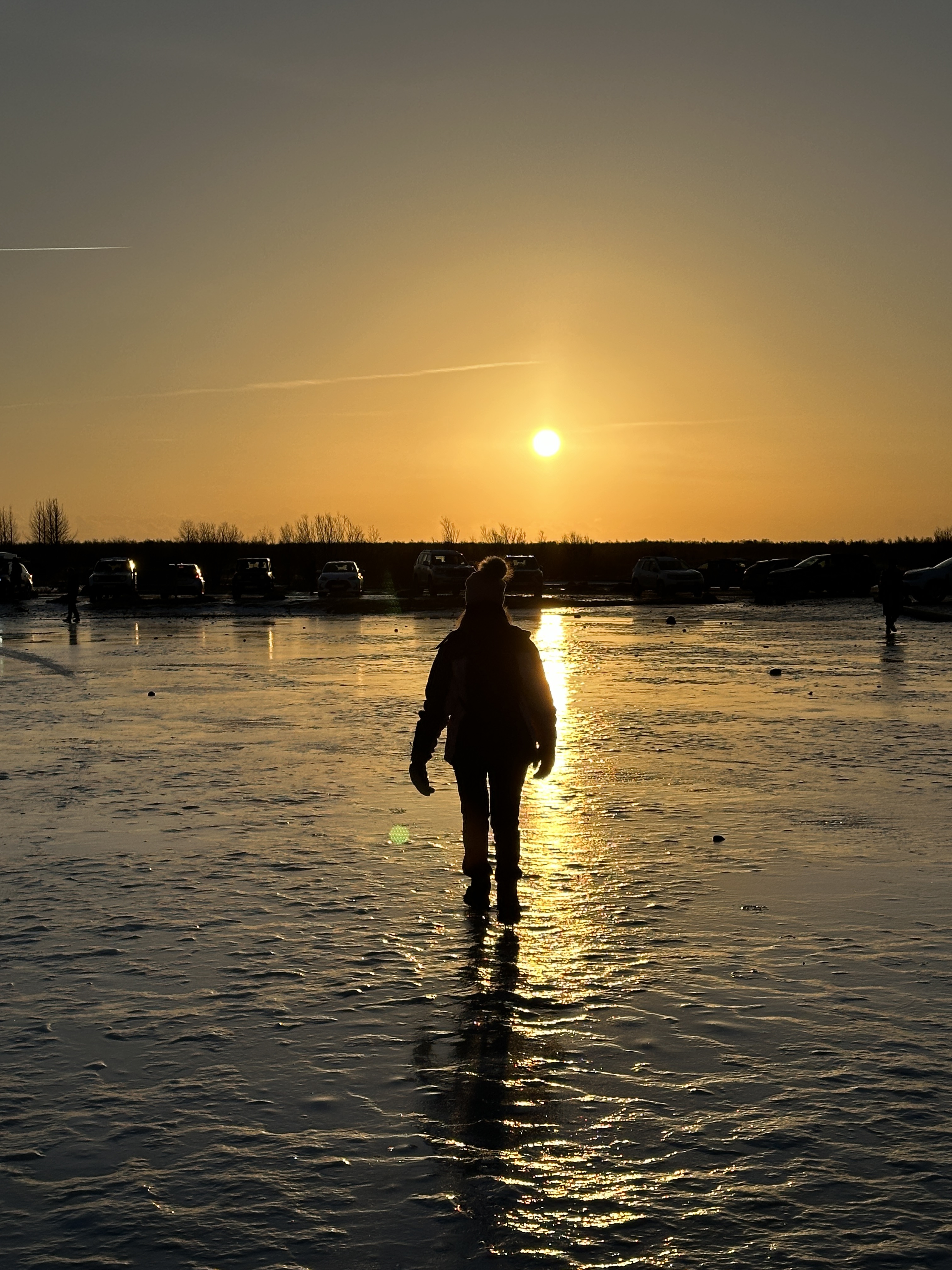 Persona che cammina su una distesa di ghiaccio al tramonto