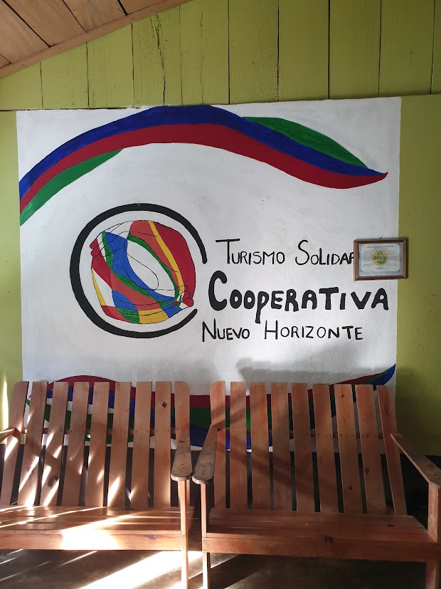 Insegna colorata della Cooperativa di Turismo Solidale Nuevo Horizonte con sedute in legno