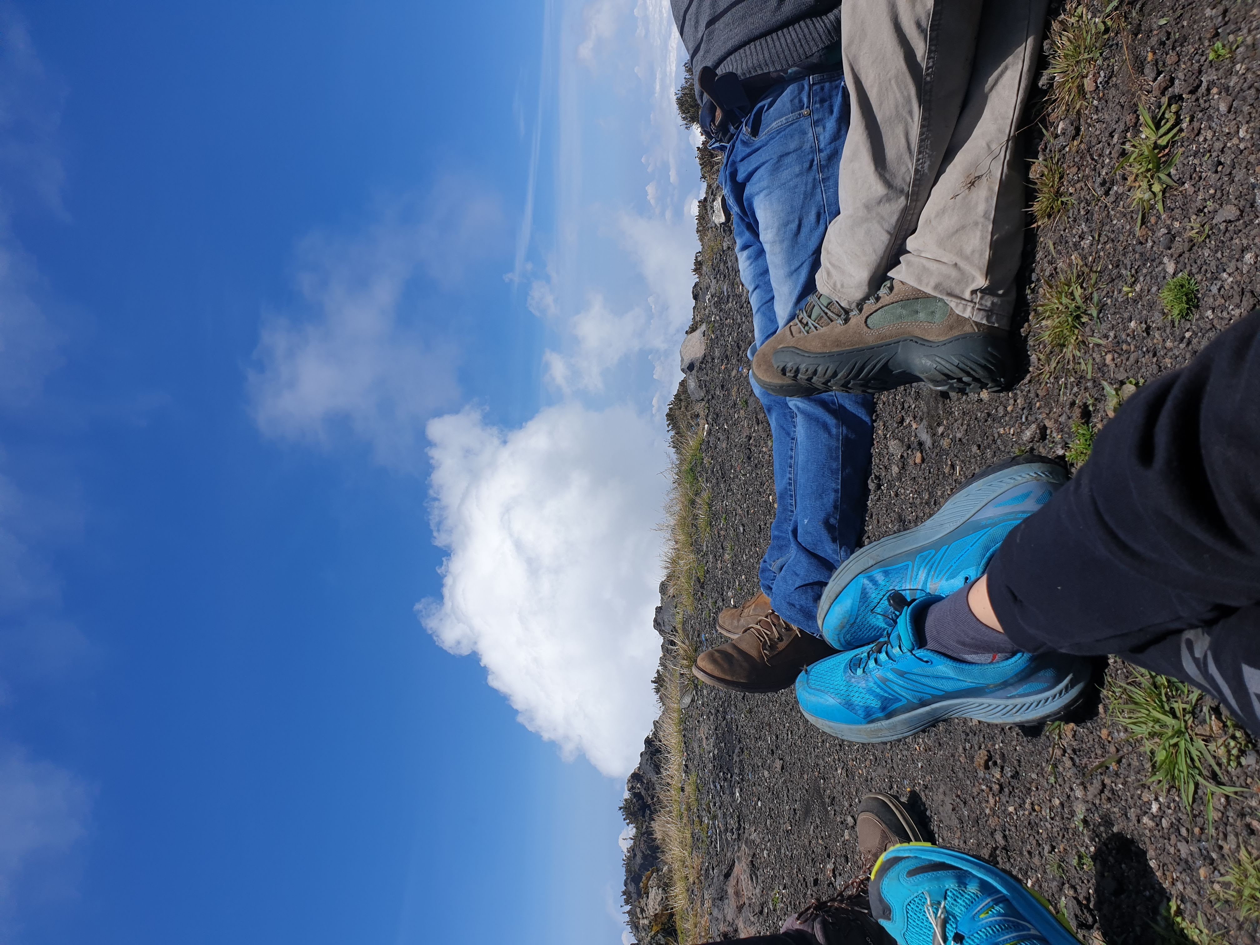 Gambe di escursionisti sdraiati a riposare sulla terra scura della cima vulcanica