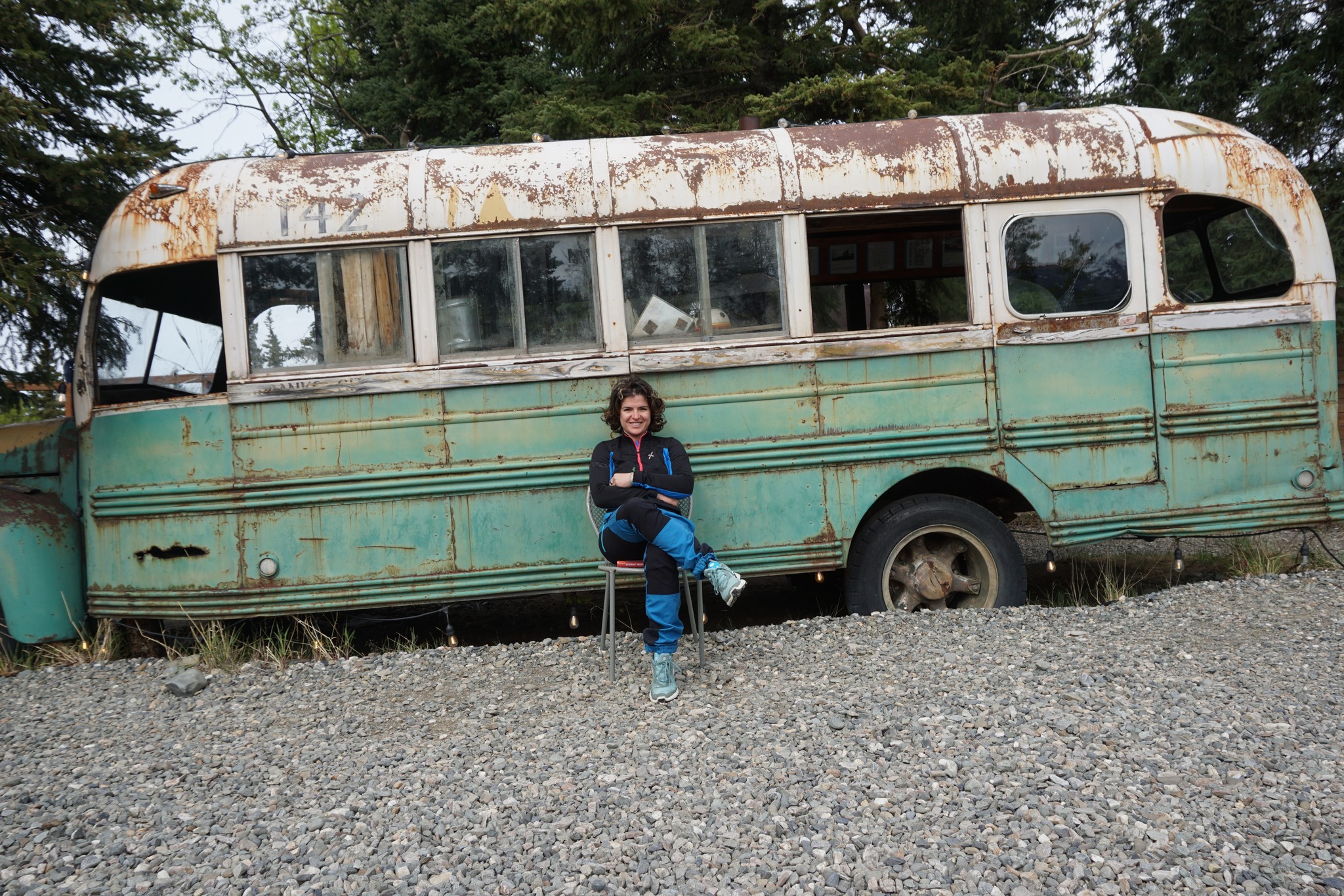 Giulia seduta davanti a un vecchio autobus verde abbandonato nella natura