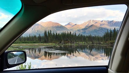 Vista dal finestrino di un'auto a noleggio su un lago e catena montuosa in Alaska