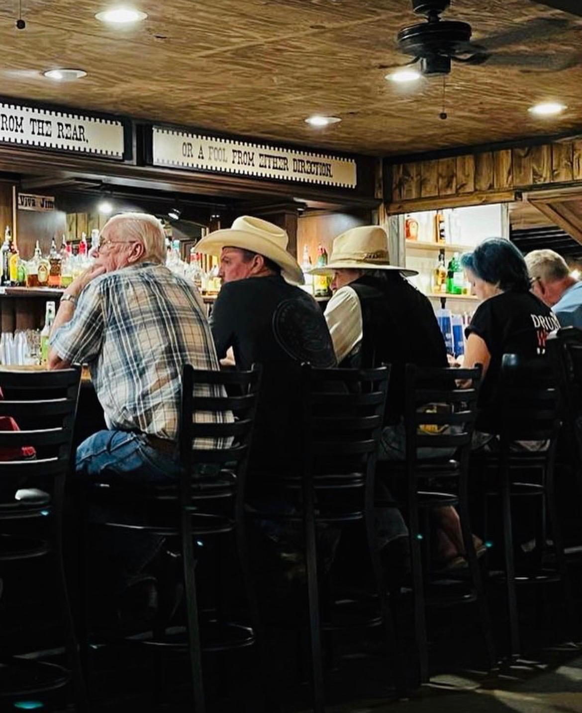 Uomini con cappello da cowboy seduti al bancone del tipico saloon western Chilleen’s on 17