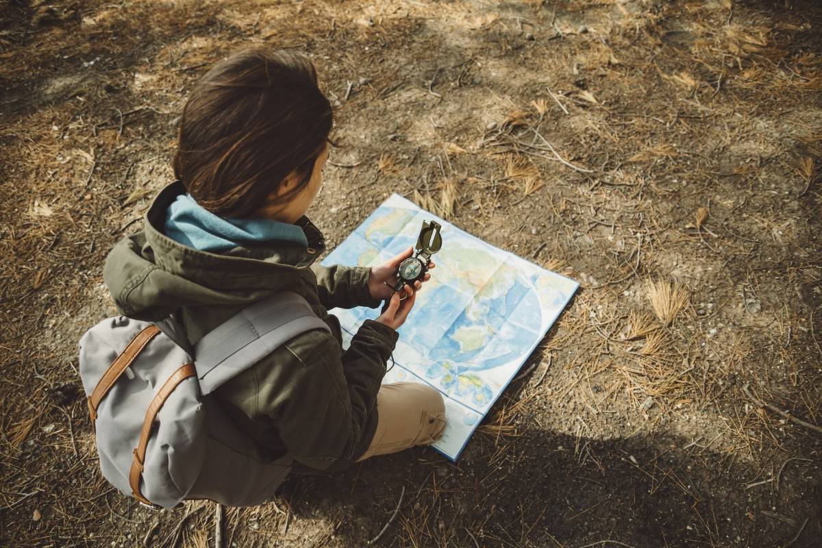 Viaggiatrice consulta una mappa con bussola nella natura