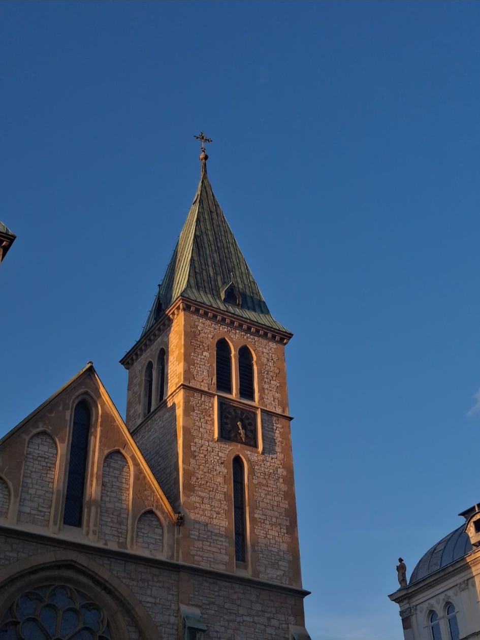 Dettaglio architettonico del campanile della Cattedrale del Sacro Cuore a Sarajevo sotto un cielo blu