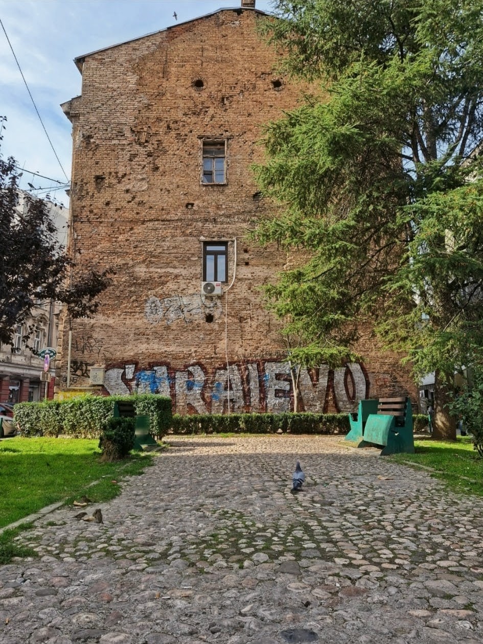 Muro di mattoni con evidenti segni di fori di proiettile, traccia dell'assedio di Sarajevo
