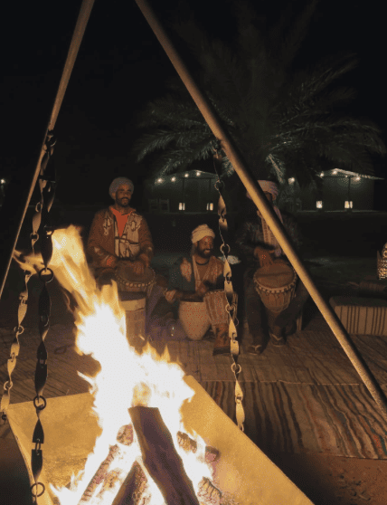 Ragazzi berberi che suonano strumenti tradizionali attorno al fuoco nel deserto