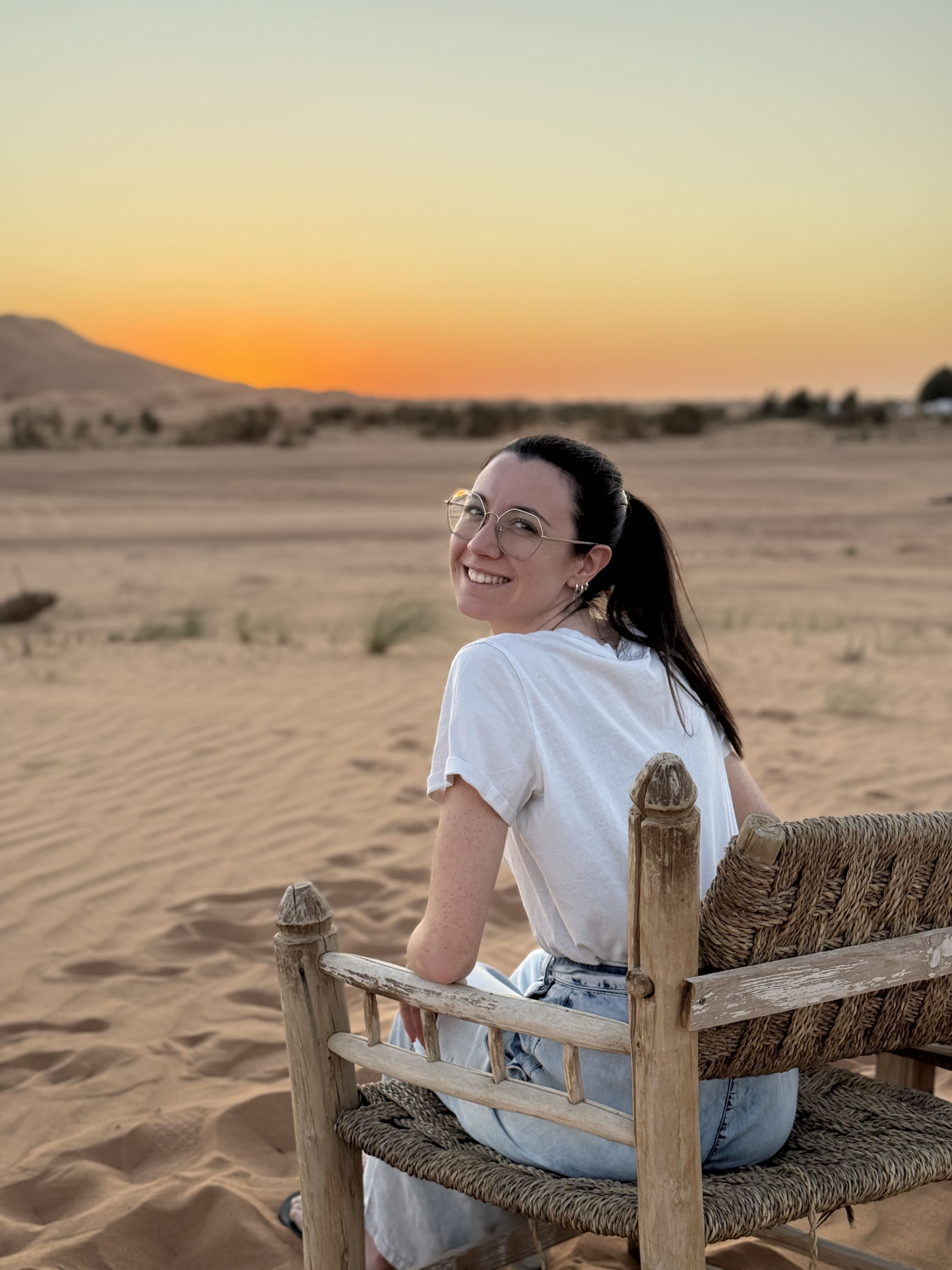 Ludovica sorridente seduta su una sedia tradizionale tra le dune del deserto