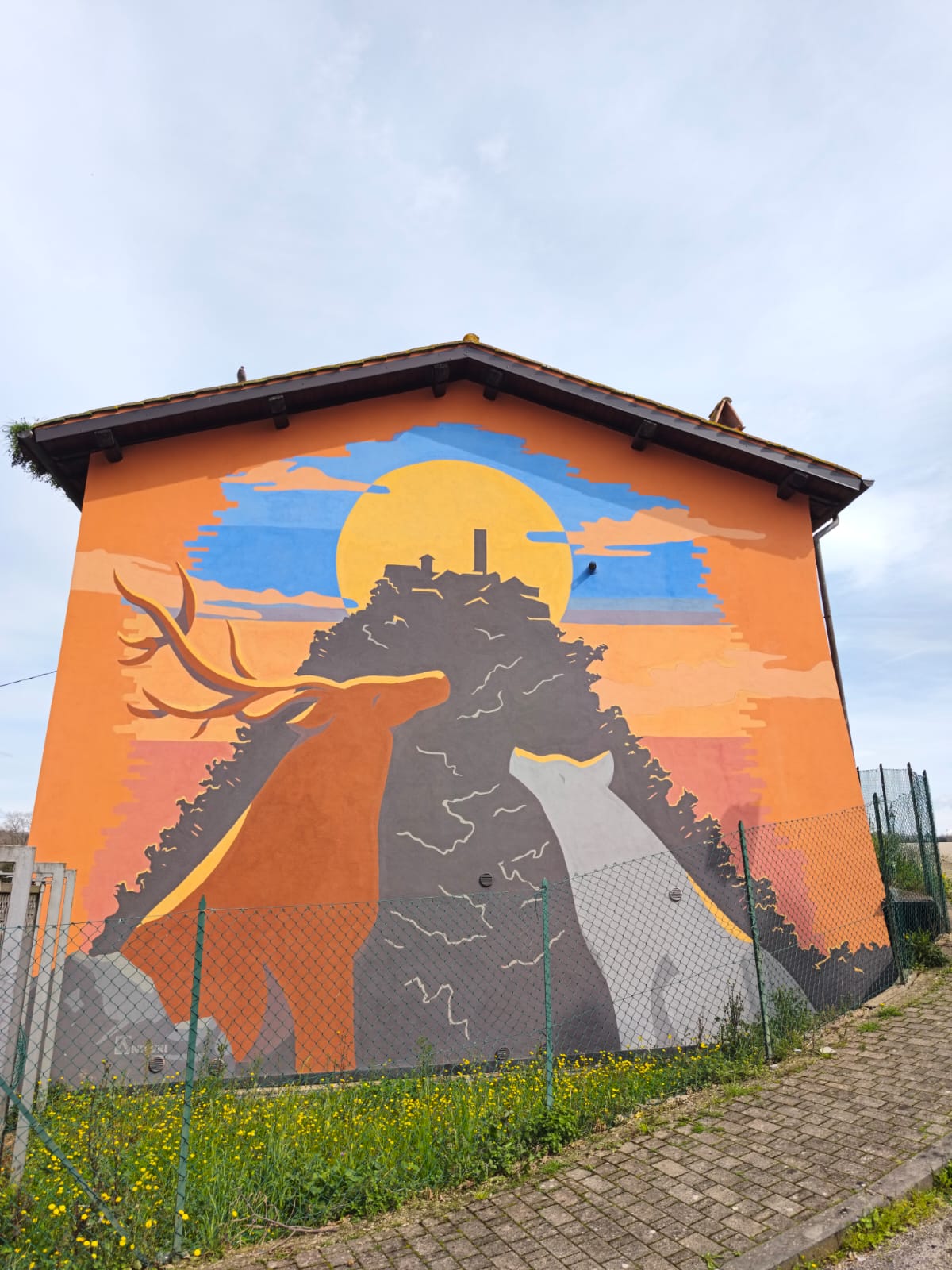 Murales raffigurante un cervo e un lupo illuminati dal sole sulla facciata di un edificio