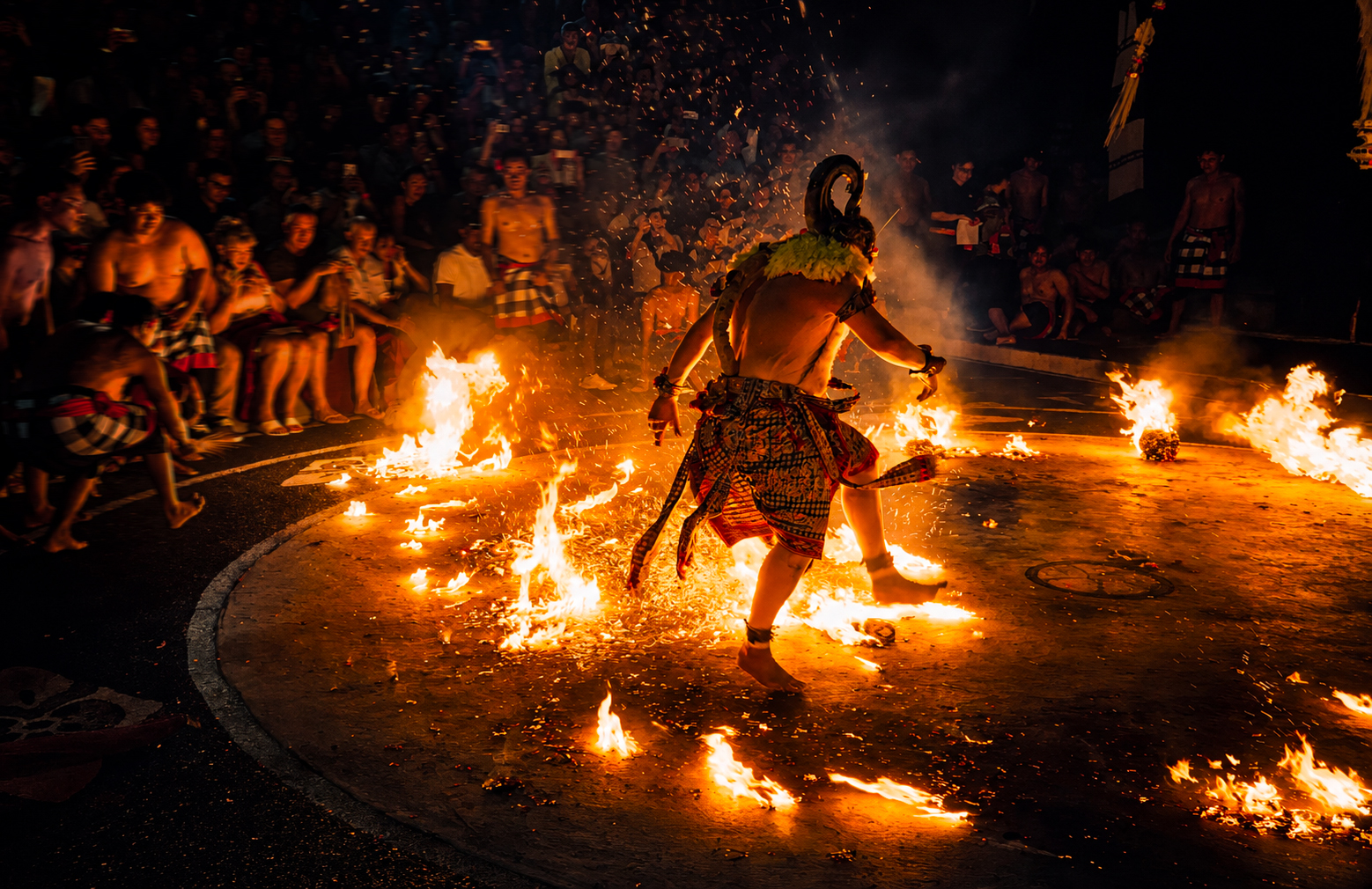 Performer della danza Kecak a torso nudo in cerchio con luci e fuoco al centro