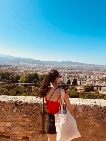 Vista panoramica dall'alto sopra i tetti bianchi e i vicoli del quartiere El Albacín a Granada, con l'Alhambra sullo sfondo sotto un cielo azzurro