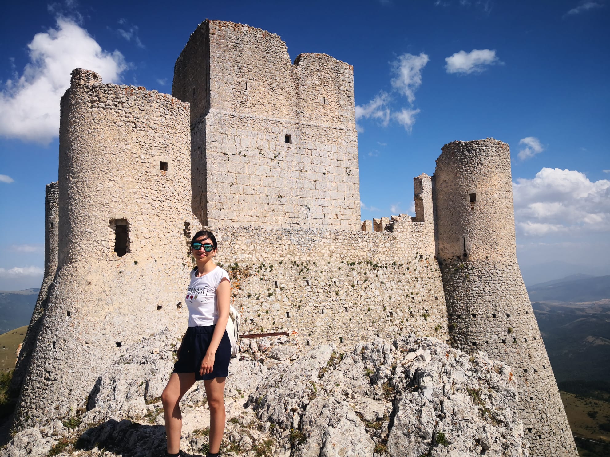 La travel designer Chiara Papa in tenuta estiva da trekking ai piedi della suggestiva fortezza di Rocca Calascio
