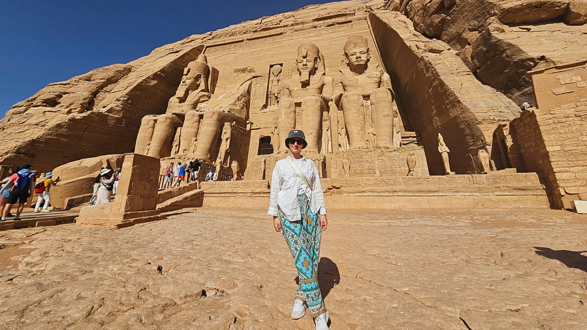 Viaggiatrice in posa davanti alla colossale e inconfondibile facciata del tempio di Abu Simbel