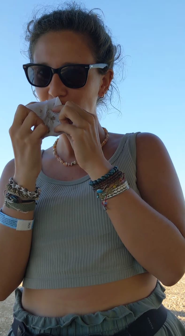 Donna locale seduta sotto una tettoia nel deserto mentre prepara il cibo