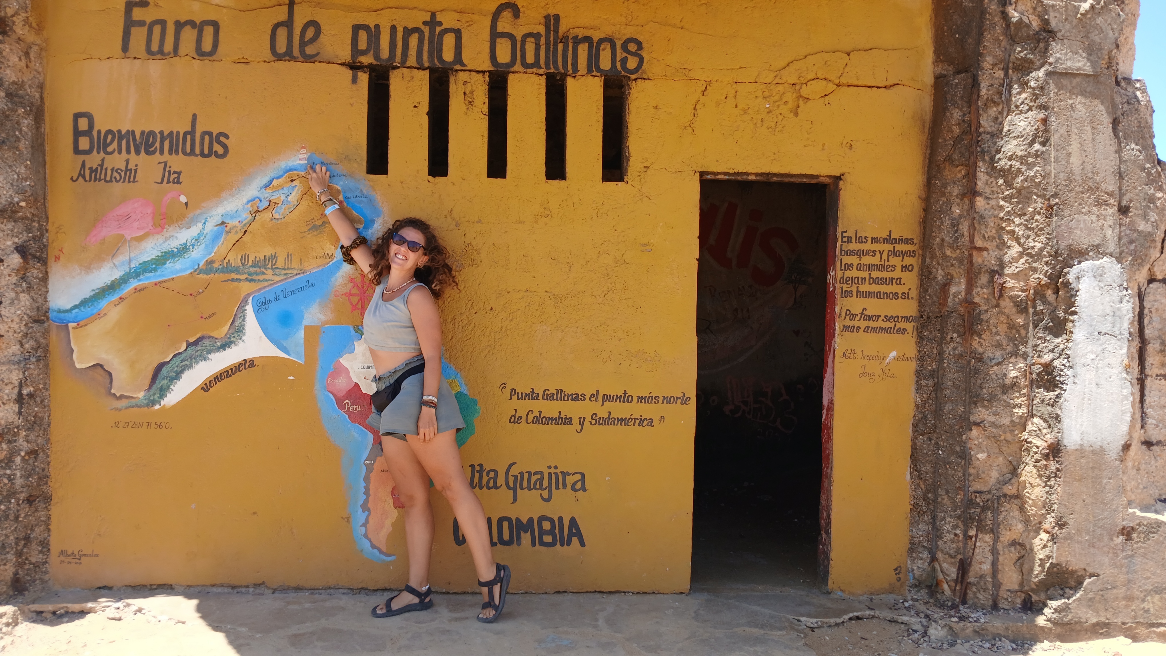 Ragazza in posa trionfante davanti all'edificio giallo del Faro di Punta Gallinas