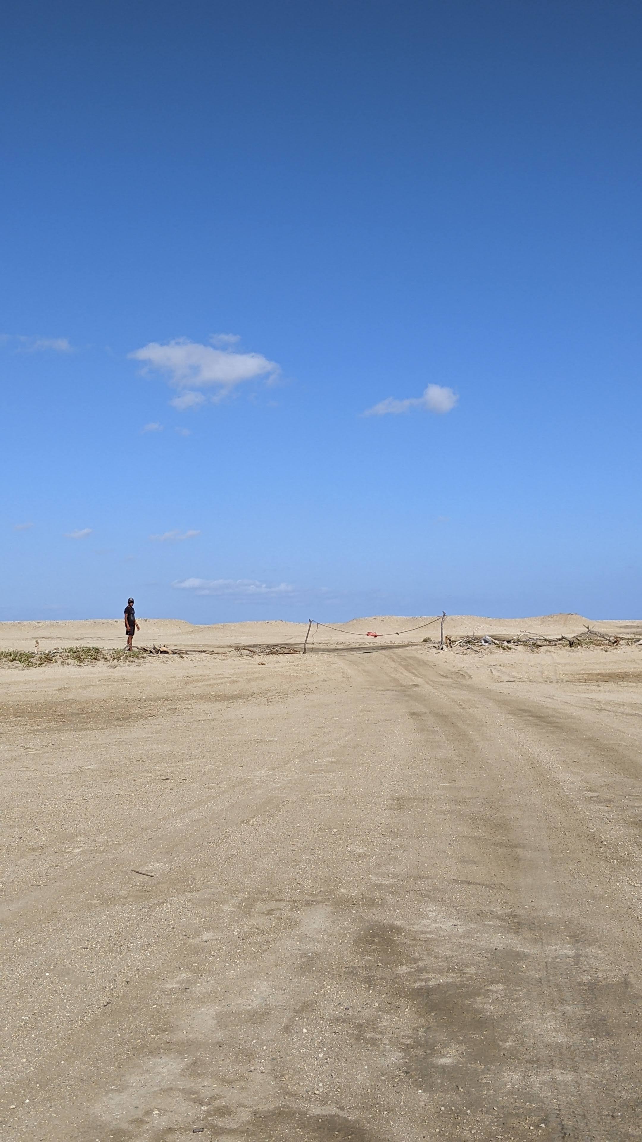Persona in lontananza che blocca la pista sabbiosa con una fune
