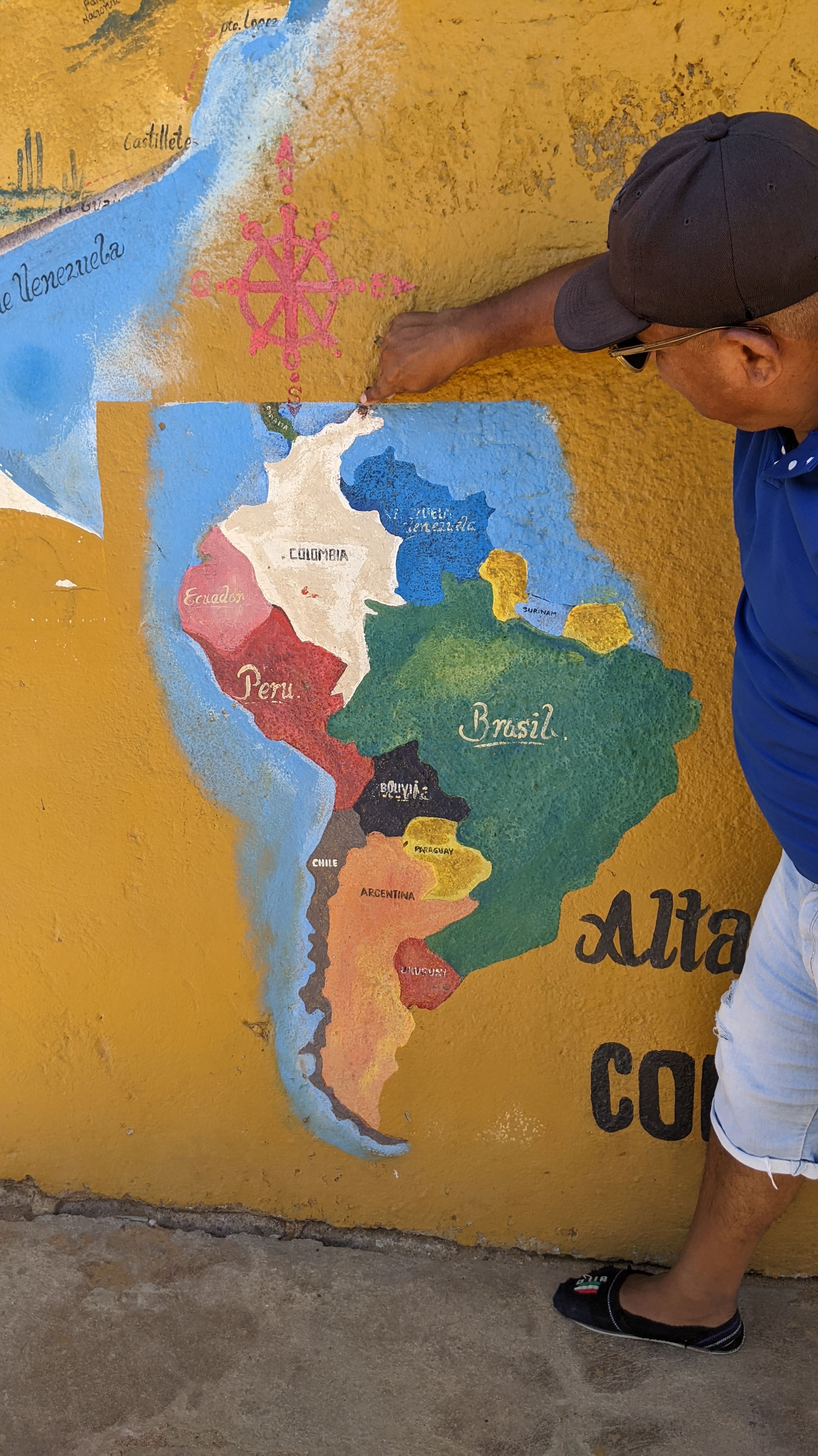 Uomo che indica Punta Gallinas su una mappa murale del Sud America