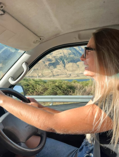 mezzo busto di una ragazza al volante in un viaggio on the road in Nuova Zelanda